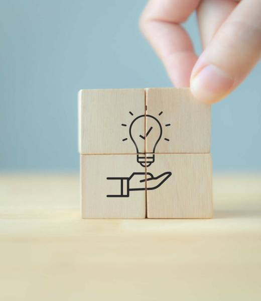 New idea, solution, suggestion concept.  Hand puts the wooden cubes with light bulb on hand icon on beuatiful grey background and copy space. Business review, strategy suggestion for business growth.