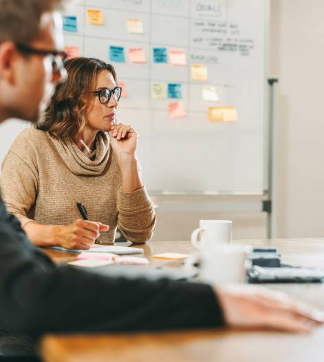 Business people in a bright office engage in collaborative brainstorming. The team discusses ideas and implements a structured framework for project management, fostering innovation in this tech startup.